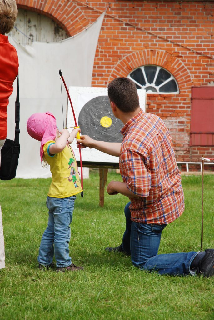 Bogenschießen klienes KIind wir von Lehrer angeleitet